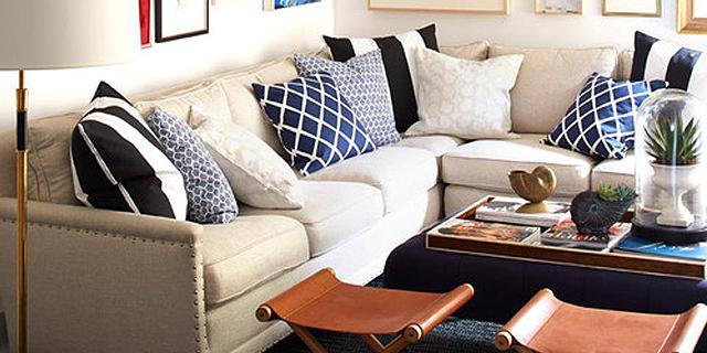An image of a corner sofa with blue accent pillows in a living room