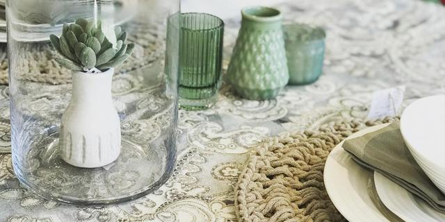 An image of a table setting with white plates and white and green glassware